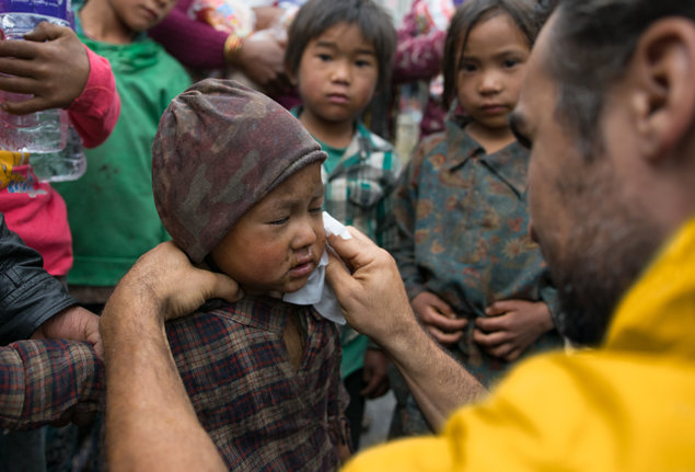 Volunteer Minister from California, Mike Savas, comforts and cleans up a young boy in Nepal